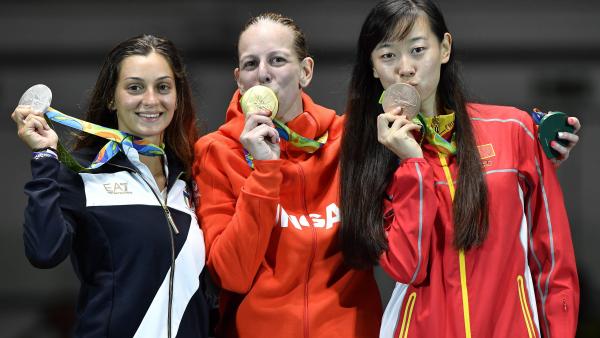 Rio de Janeiro, 2016. augusztus 6.
A párbajtõrben olimpia bajnok Szász Emese (k) megcsókolja aranyérmét az eredményhirdetésen, mellette a második helyezett olasz Rossella Fiamingo (b) és a bronzérmes kínai Szun Ji-ven a Rio de Janeiró-i 3-as Karióka Arén