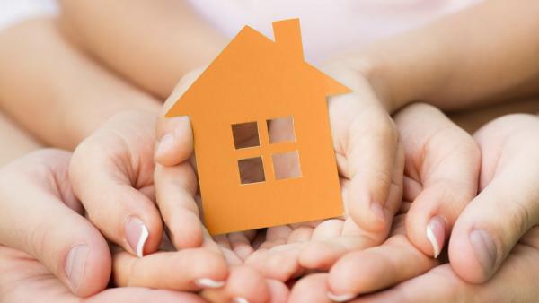 Family holding green paper house in hands. Real estate concept
