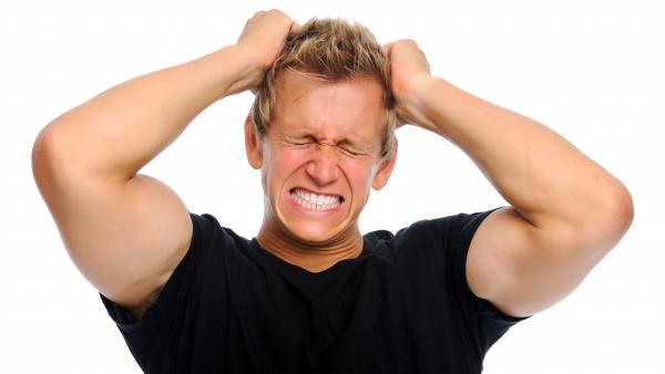 Young man clenching his teeth, pulling his hair, suffering from stress