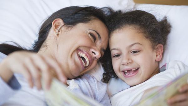 Hispanic mother reading book to daughter