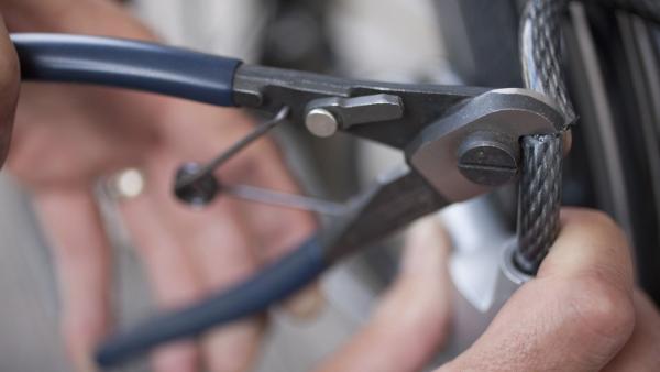 Germany, Bavaria, Munich, Mature man cutting bicycle lock with wire cutters