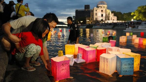 Mécsest gyújt egy férfi és lánya az áldozatok emlékére a hirosimai Béke Emlékparkban  (fotó: MTI/EPA/Majama Kimimasza)