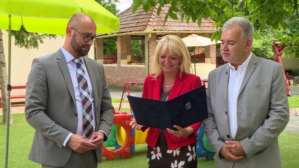 Fülöp Péter helyettes államtitkár, Pribelszki Péterné óvodavezető és Nagy Ferenc alpolgármester az elismerő okirat átadásán. Fotó: 7.TV/Kovács Dénes