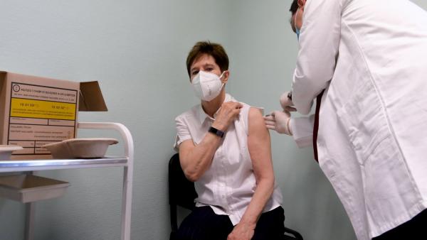 Szlávik János infektológus főorvos beoltja a Pfizer és a BioNTech által kifejlesztett koronavírus elleni oltóanyaggal Kertész Adrienne osztályvezető főorvost a Dél-pesti Centrumkórházban 2020. december 26-án. Magyarországon Kertész Adrienne kapta meg az e