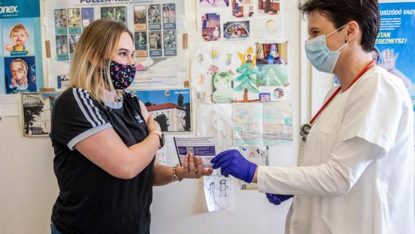 Nagy Gabriella orvos (j) átadja az oltási igazolást egy fiatalnak, miután beoltották a német-amerikai fejlesztésű Pfizer-BioNTech koronavírus elleni oltóanyag, a Comirnaty-vakcina első adagjával az orosházi Dr. László Elek Kórház és Rendelőintézetben kial